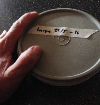 Min hand vid en matlåda med en tejpbit som det är textat "Lasagne 22/5 -16" på Matlåda med kycklinglasagne