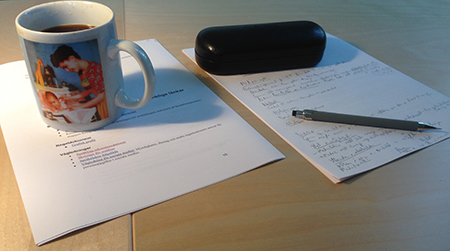 Papper, penna, glasögonfodral och kaffemugg Papper penna och kaffemugg