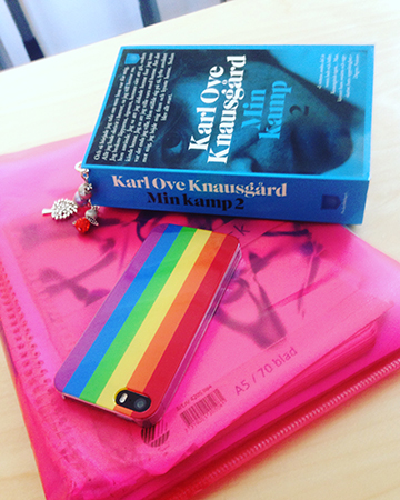 Boken Min kamp 2, röd plastmapp och mobil med regnbågsskal Bok mapp och mobil