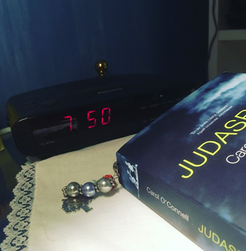 Klockan 7.50 i röda digitala siffror och bokens Judasbarn Klockan 7.50 i röda digitala siffror och bokens Judasbarn