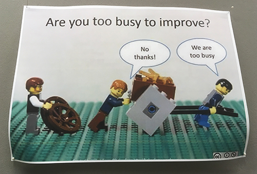 Skylt med legodockor och texten "Are you too busy to improve?"