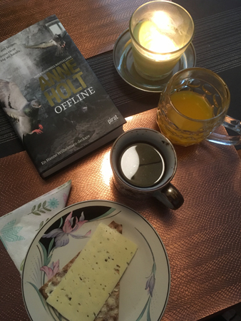 Frukost med knäckemacka med ost, kaffe, tänt ljus och bok