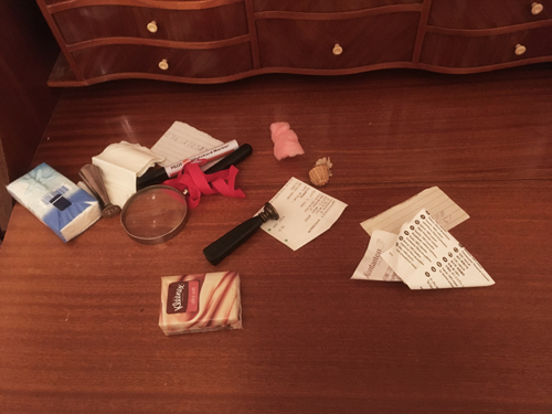 Diverse papper , ett förstoringsglas och småsaker på en skrivskiva till en sekretör i mahogny