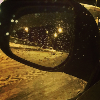 Regn på bilrutan och backspegeln, kväll vinter