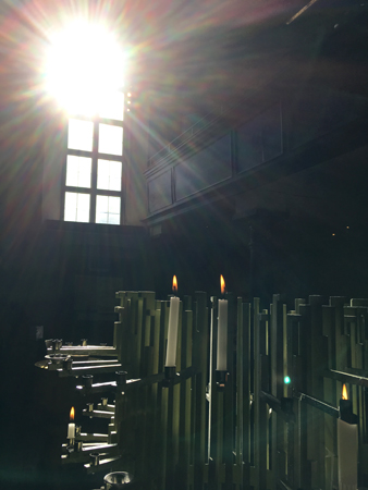  Sol genom ett kyrkfönster och två tända ljus