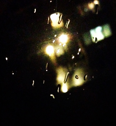 Regn på fönster och lampor utanför i mörkret