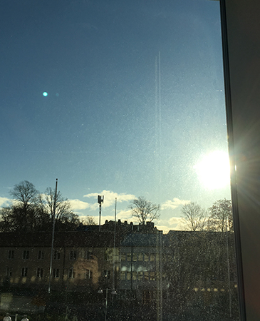 Solen skiner utanför ett skitigt jobbfönster