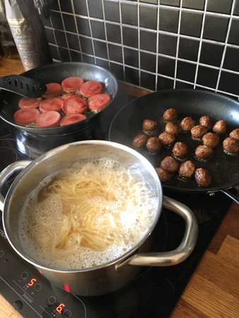 Kycklingkorv köttbullar och pasta på spisen