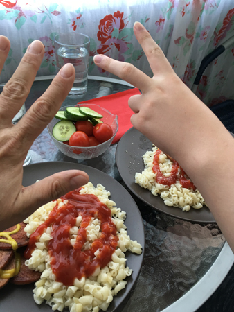 Elias och jag äter makaroner och korv på balkongen