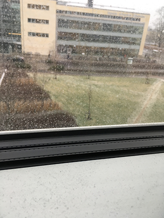 Snö utanför och damm innanför kontorsfönstret