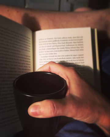 Uppslagen bok och kaffe på sängen