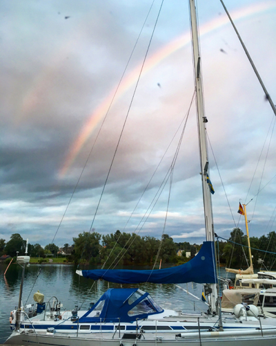 Regnbågen bakom båtarna i Motala hamn