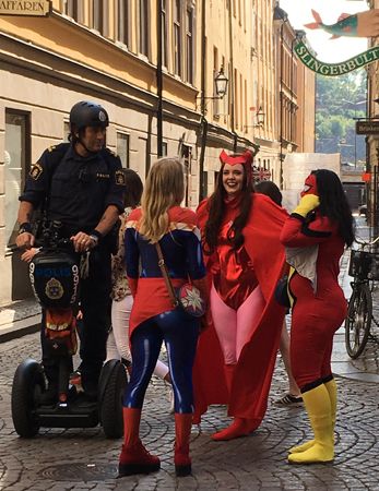 Polis och tre tjejer utklädda till djävlar i Gamla stan