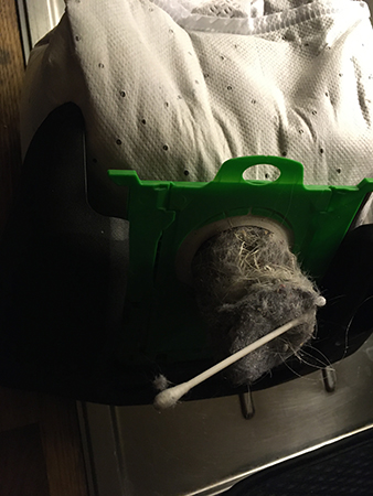 Överfull dammsugarpåse där en dammkorv sticker fram med en topz på toppen