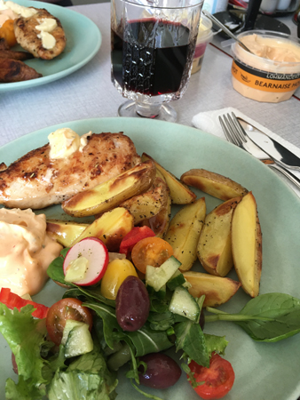 Stekt kycklingfilé potatisklyftor grönsaker och ett glas Amicone