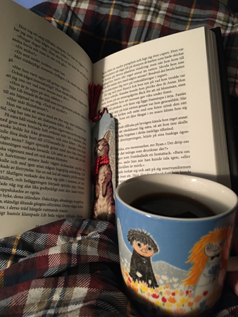 Bok med kattbokmärke och muminmugg med kaffe