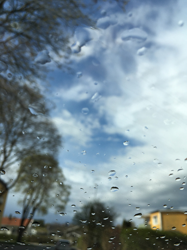 Regndroppar på fönstret o ljusblå himmel Regndroppar på fönstret o ljusblå himmel
