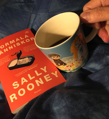 Boken Normala människor och kaffemugg på sängen