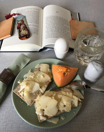 Lunch knäckemackor med ost melon ägg vatten och en bok