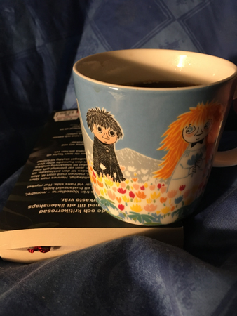 Bok och kaffemugg på sängen