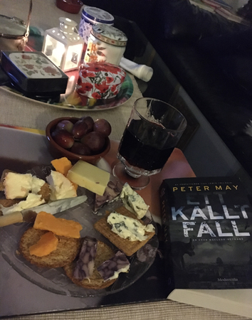 Ostassiett med röda druvor vin och boken Ett kallt fall