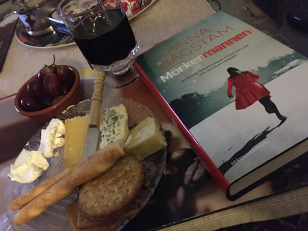 Ostassiett vin druvor och boken Mörkermannen