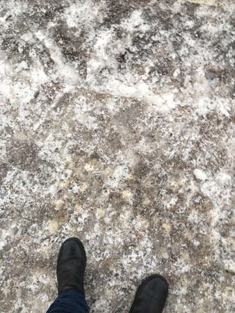 Mina fötter i vinterbootsen på isig trottoar