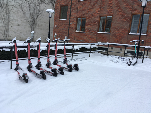 Elscootrar i ställ och en utanför