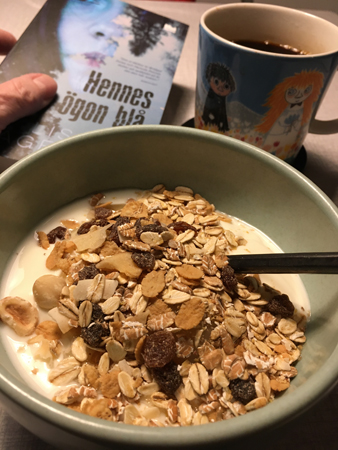Frukost med yoghurt o müsli kaffe o boken Hennes ögon blå