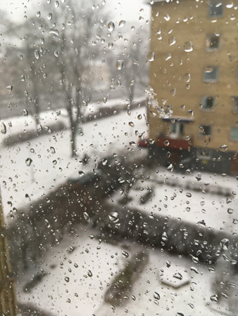 Snö utanför droppar på fönsterrutan