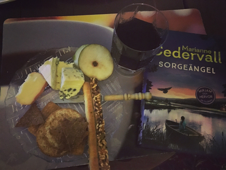 Ostassiett med kex och päron vin och boken Sorgeängel