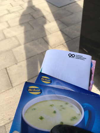 Min skugga på plattor varma koppenpaket o tidning i handen