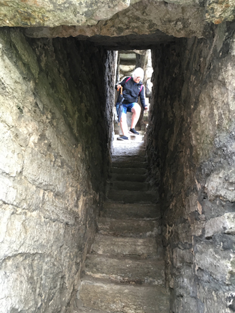 Anna klättrar i en smal trappa i St Clemens kyrkoruin