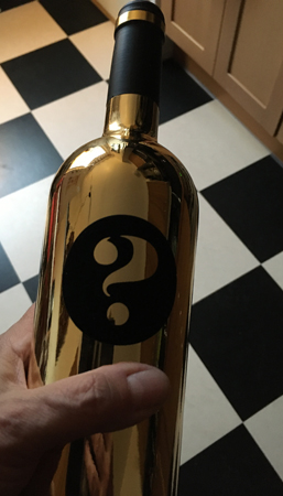 Vinflaska i guld med frågetecken på Its a Zin