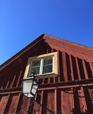 Blå himmel över rött trähus med lykta Gamlis