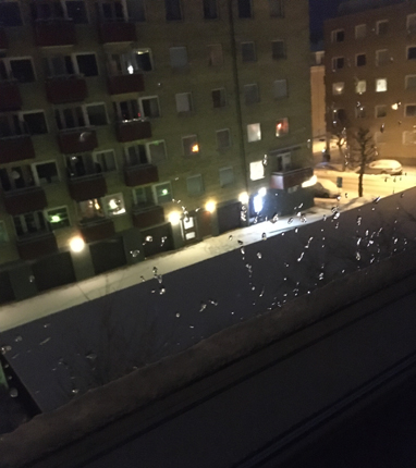 Genom köksfönstret droppar på fönstret snö utanför