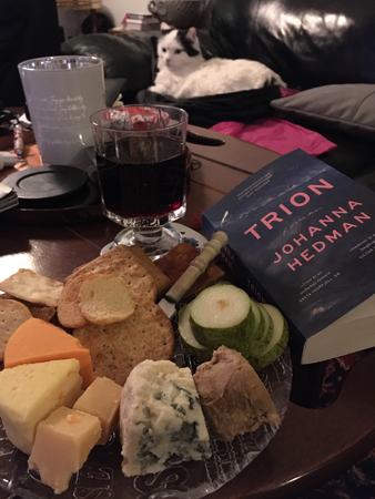 Ostassiett rödvin och boken Trion Citrus i soffan