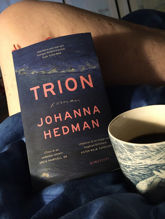 Söndagsmorgon med boken Trion och kaffe på sängen