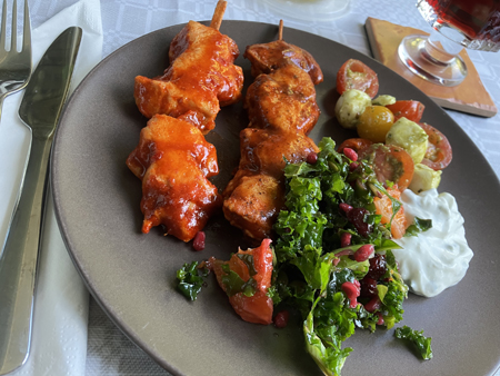 Kycklingspett sallader tzatziki och ett glas rött