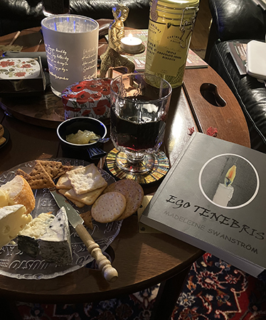 Ostassiett vin och boken Ego tenebris