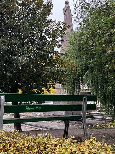 Bänk med texten Älska mig och en staty i bakgrunden