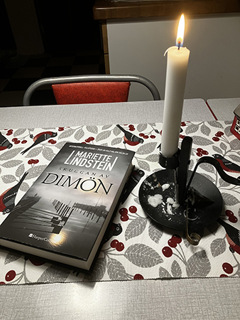 Boken Skuggan av Dimön och ett tänt ljus på köksbordet