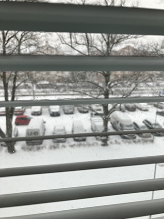 Snöig parkering genom persiennerna