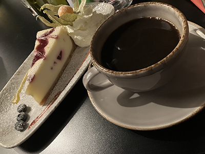 Cheesecake med hallon i och blåbär bredvid o kaffe