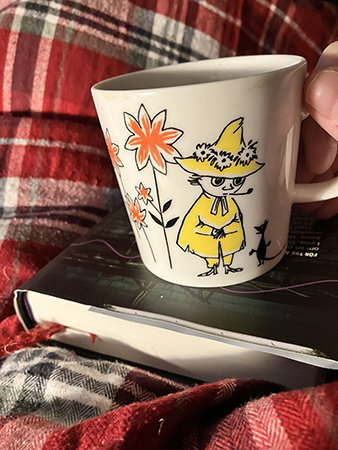 Muminmugg på bok i sängen