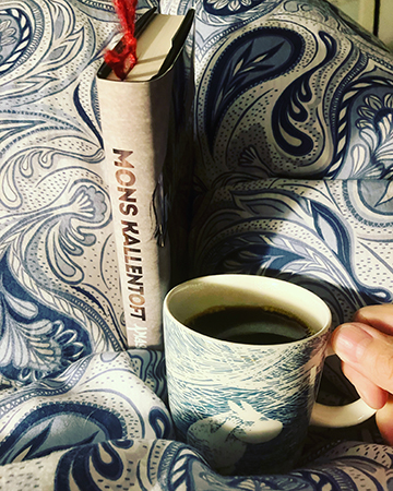 Boken Amason och kaffe på sängen i Muminstormmugg