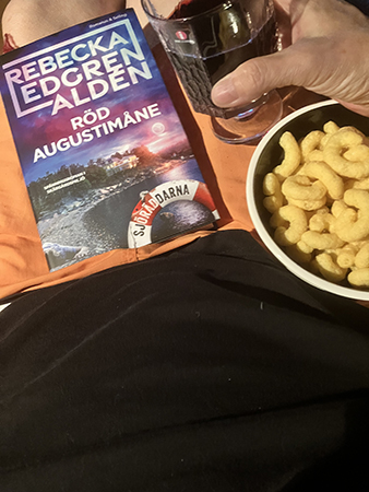 Boken Röd augustimåne stiltonbågar och ett glas rött