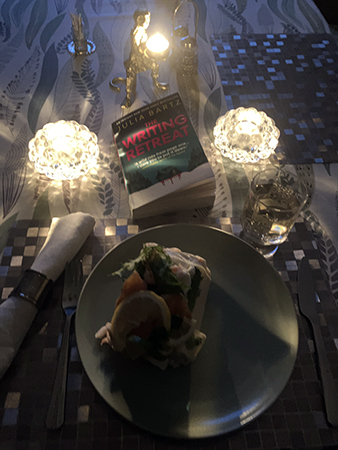 Räksmörgåstårtbit tända ljus och boken The writing retreat