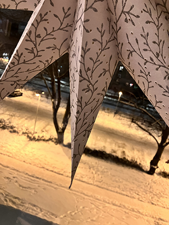 Spetsar på en pappersstjärna i ett fönster o snö utanför