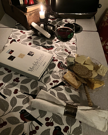 Ostassiett ett halvt glas rött tänt ljus o boken Meddelande